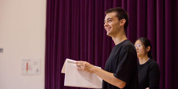 Man holding a script, looking up and smiling