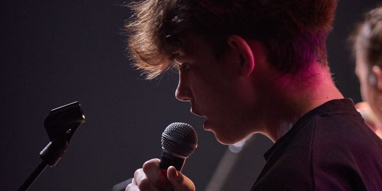 A young boy singings into a held microphone