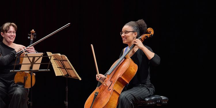 Two strings students on stage laughing