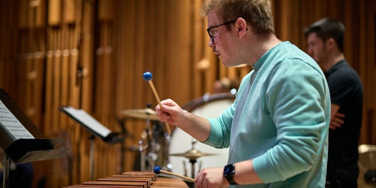 Student playing xylophone on stage as part of the orchestra