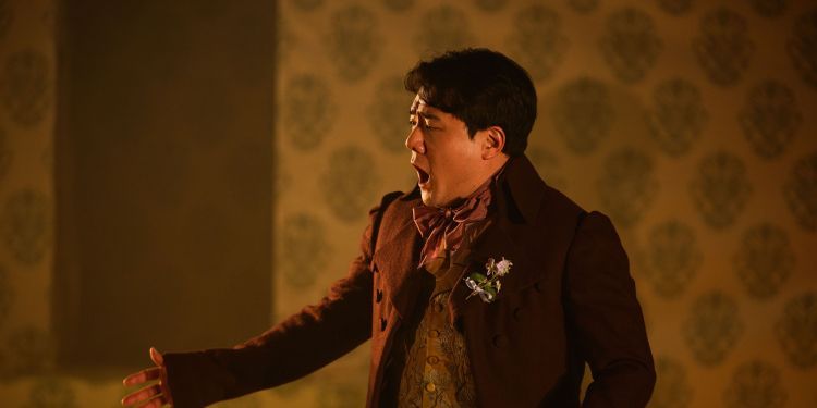 Vocal student on stage singing wearing a brown suit