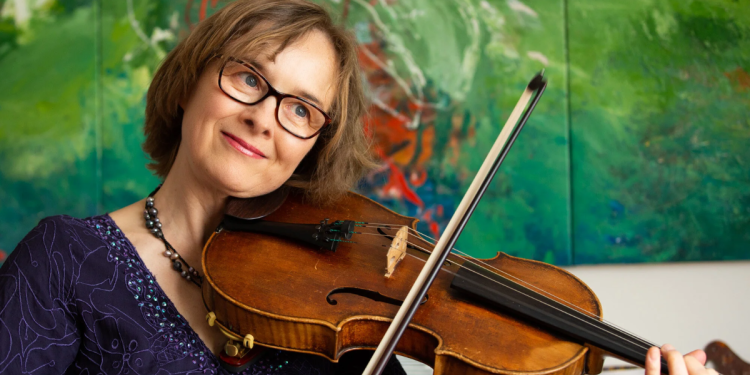 Caroline Henbest playing the viola smiling at the camera