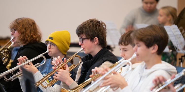 Four young musicians playing the trumpet in an ensemble