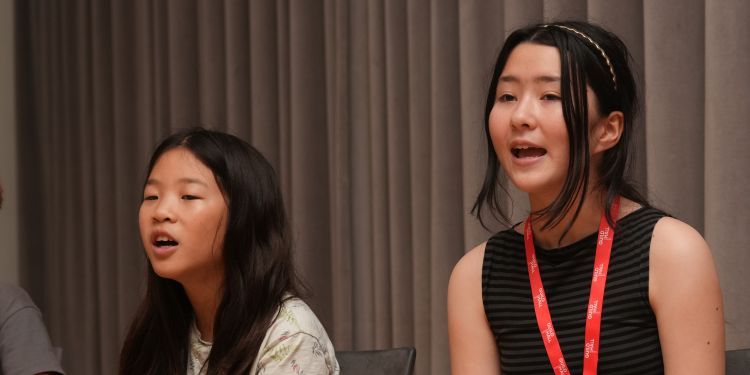 Two young girls in the middle of singing