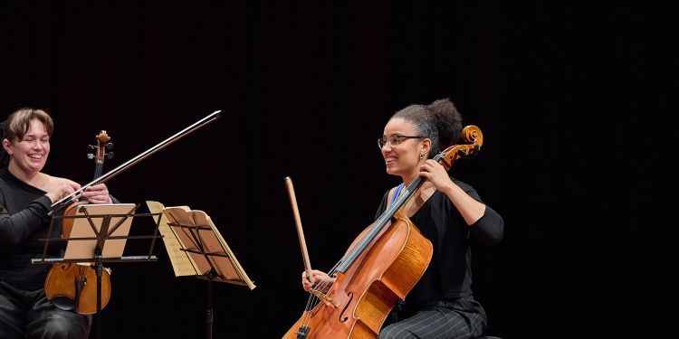 Strings students on stage smiling and talking