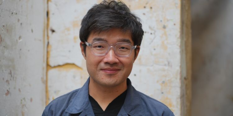 headshot of Dr Weida Wang (short black hair, clear glasses, wearing a black tshirt and blue blazer)