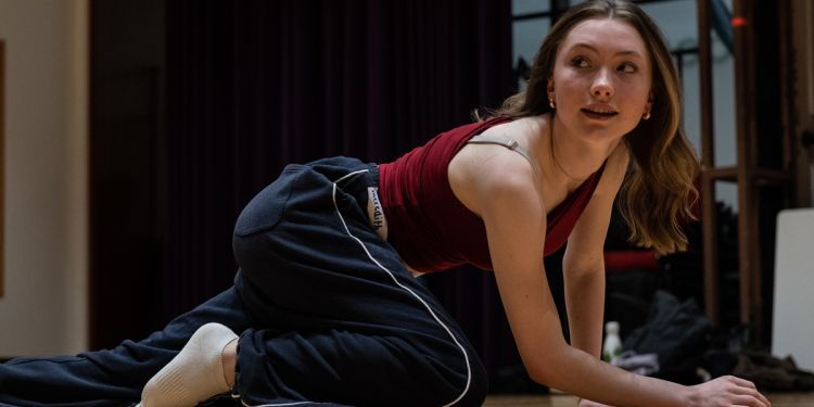 A young actor crawling on the floor in a studio space