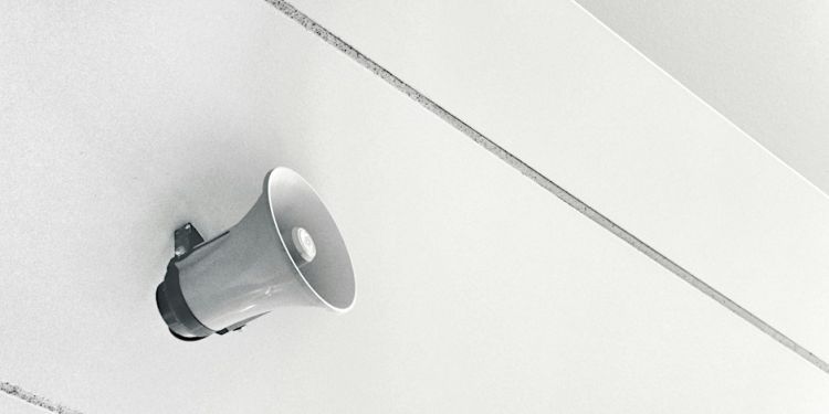 Black and white image of a speaker attached to a wall