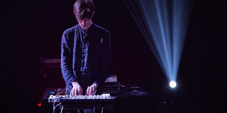 Electronics student stood up looking down at a piano and sound desk