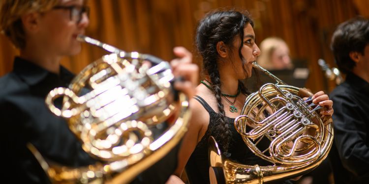 Two young musicians play the french horn in Barbican Hall