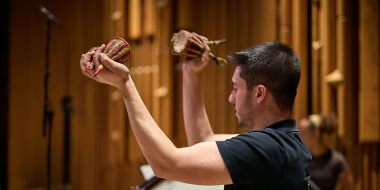 Student playing percussion in an orchestra on stage