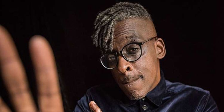 Cleveland Watkiss posing at the camera wearing a purple suit