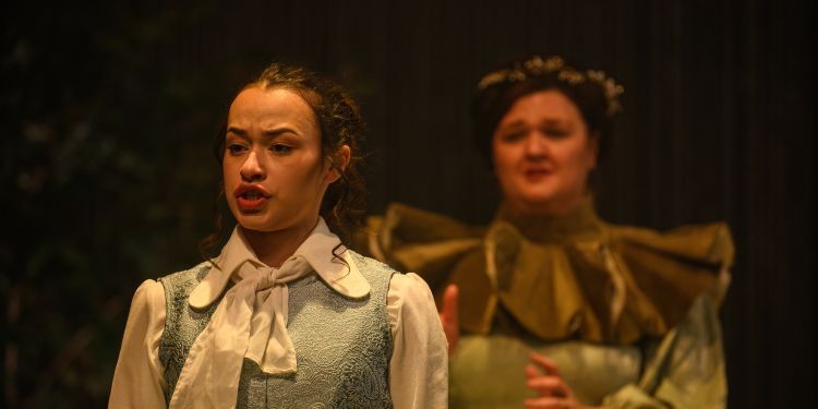 Two female presenting vocal students on stage