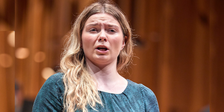 Female presenting singer on stage wearing a blue top