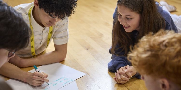 four participants on the floor writing on a piece of paper
