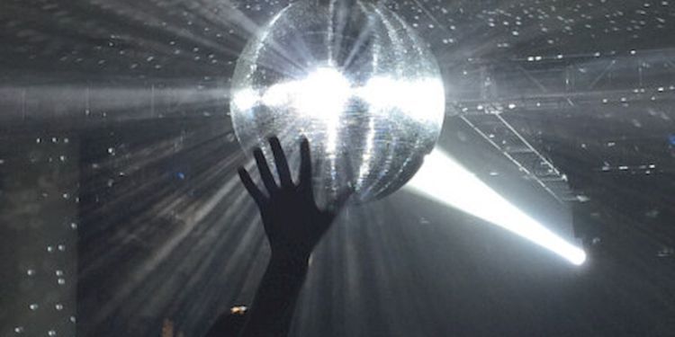 A hand touching a shimmering disco ball