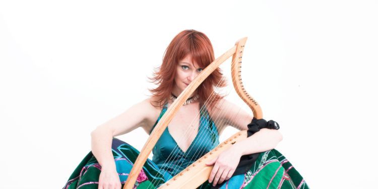 Joy Smith wearing a blue dress holding a harp