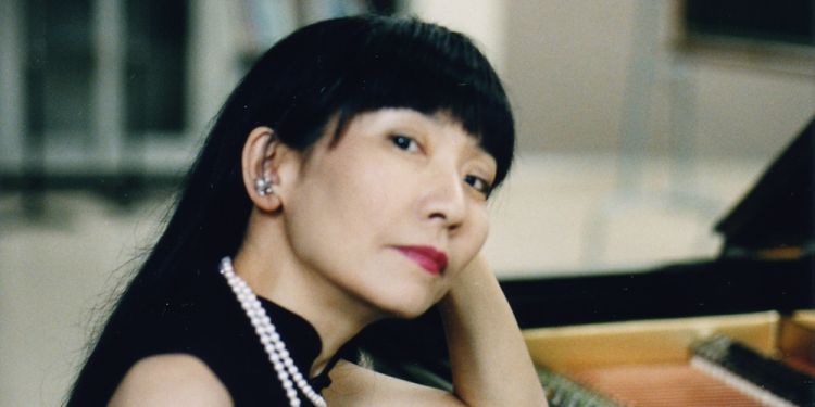 Satoko Inoue headshot sat next to a piano