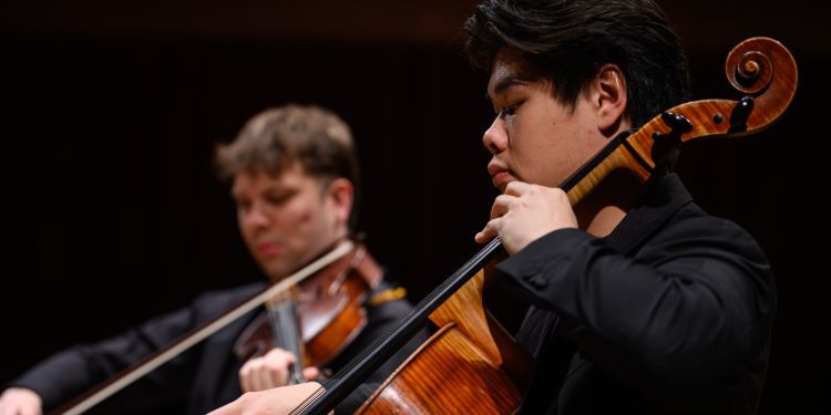 Two strings students performing on stage playing cellos