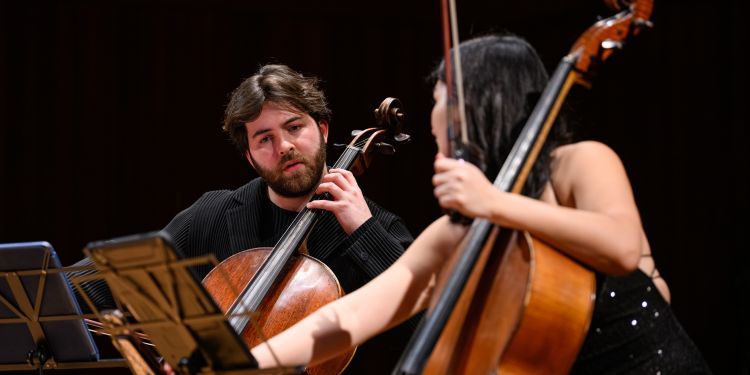 Cello players on stage discussing 
