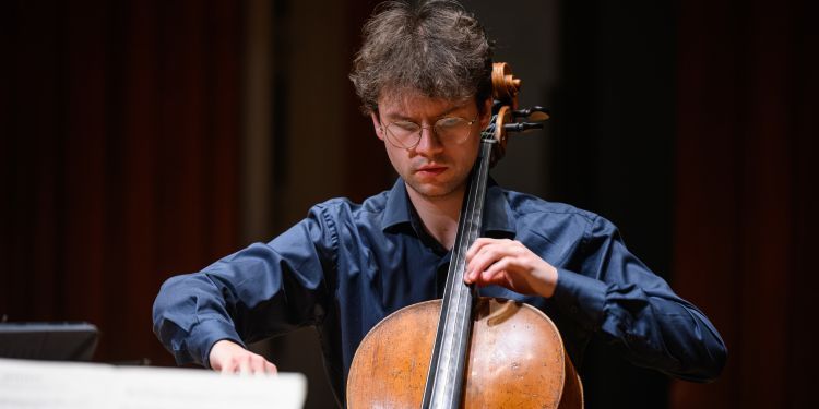 Cello student wearing a blue shirt performing on stage