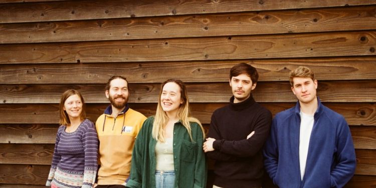 group shot of Novos Londrinos  standing in front of a wooden wall