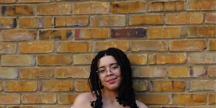 Taylor Mitchell standing in front of a brick wall smiling