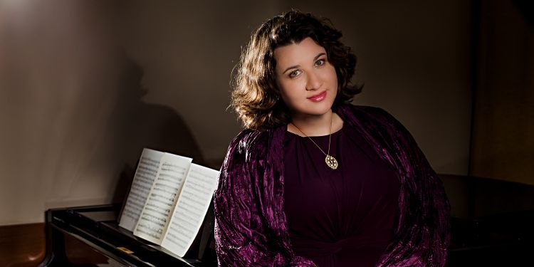 Female pianist leaning on a piano, smiling 