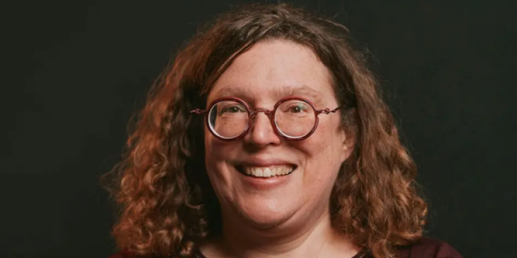 Emily Doolittle smiling at the camera wearing round glasses