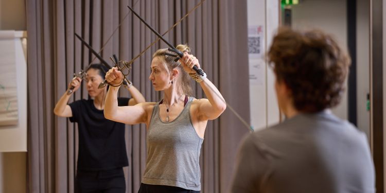 Two women are standing holding swords above their heads