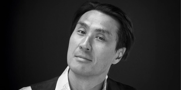 Black and white photo of Hyung-ki Joo wearing a suit and smiling