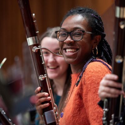 Wind players smile at the camera while holding instruments