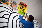 person pasting colourful poster to a wall
