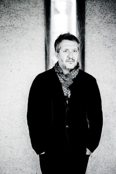 Thomas Adès stands with his hands in his pockets. The image is in black and white