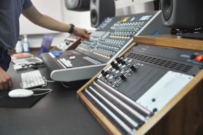 Electronic music student at a mixing desk in a studio