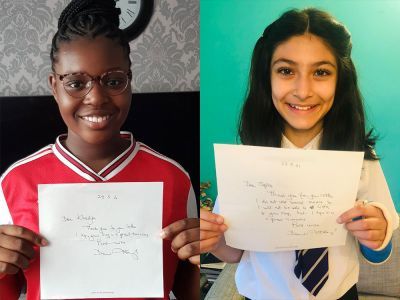 Two students holding letters