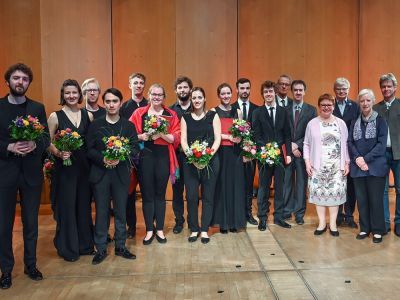image of performers stood smiling in a row holding flowers
