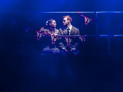 Couple on stage in vintage clothing, with Union Jack bunting