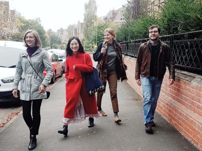 Three women and one man walking down the street smiling