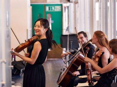 student playing the violin smiling at camera