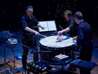 Three men playing large percussion during a performance