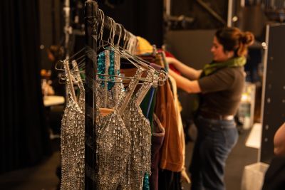 Rail of costumes with student working in the background