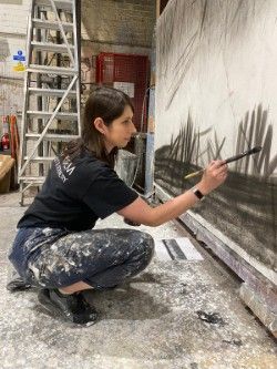 Production Arts student painting on a large canvas