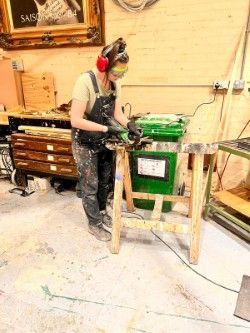 Production Arts student wearing protective eye goggles and ear muffs whilst working with wood