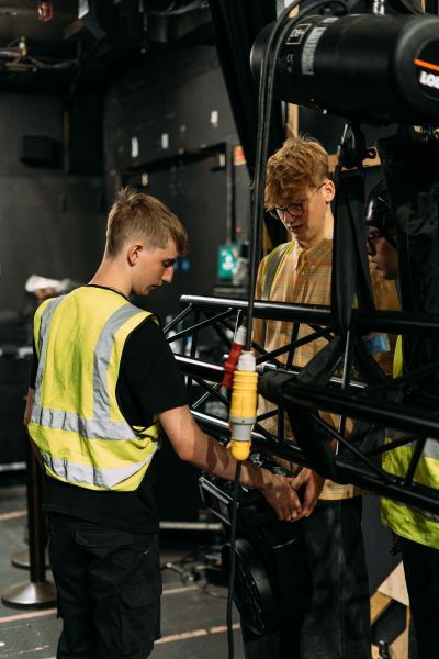 Student in high visibility vest back stage with equipment