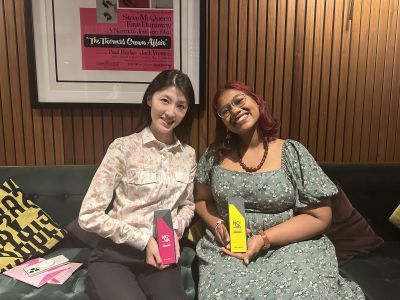 Two students sitting backstage with awards