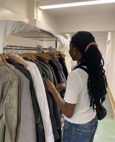Costume student standing next to rack of clothes 