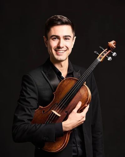 Jordan Sian holding a viola and smiling at the camera