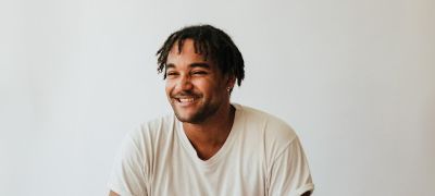 Aaron Azunda Akugbo wearing a white tshirt smiling and looking to the left of the camera