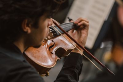 Close up shot of a young boy playing the violin, taken from behind